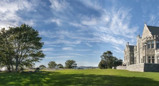 Panoramic view of the Branford Mansion and lawn at UConn's Avery Point campus on a sunny summer day. The Branford Mansion is a large, gray stone building.