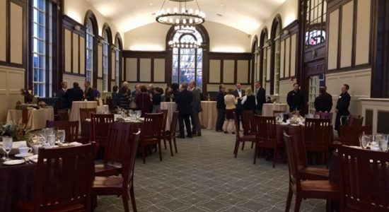 People mingling among banquet tables in Wilbur Cross North Reading Room