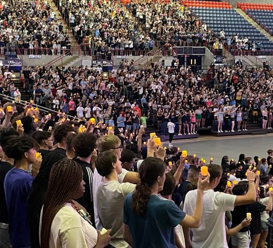 Students stading in Gampel Pavilion holding up votive candles during a Convocation ceremony