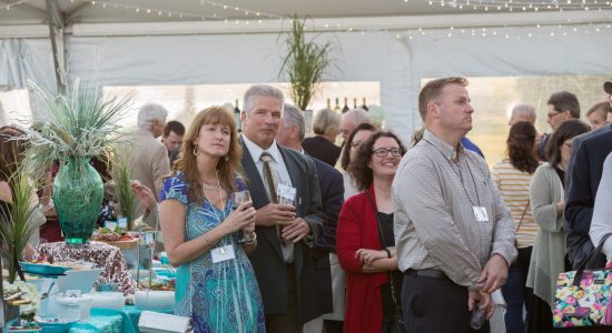 Guests mingling in an outdoor tent in the daytime. Seashore themed table displays are visible in the background.