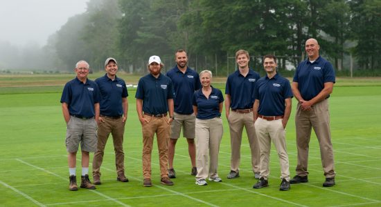 Members of the UConn Turfgrass team standing on an outdoor turfgrass field grid