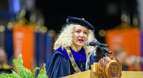 UConn President Radenka Maric in regalia speaking at a podium during a commencement ceremony