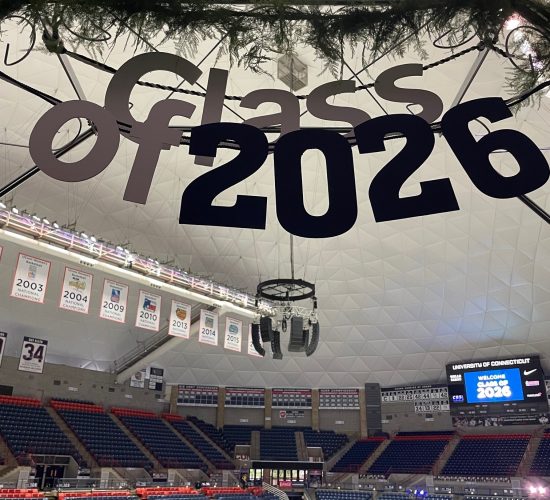 Gampel Pavilion interior with a Class of 2026 sign and greenery hanging above an entryway before a Convocation ceremony