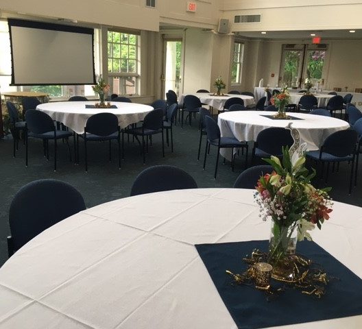 Banquet hall with tables featuring floral centerpieces before a 2023 Dose Finding Conference event