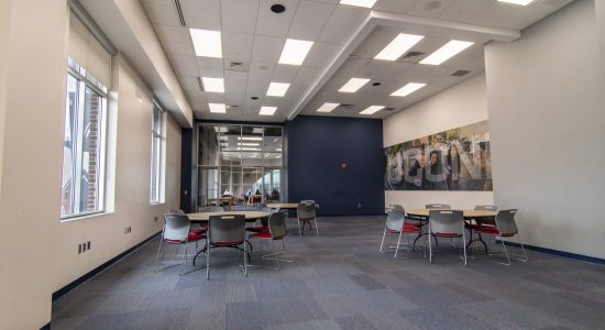 UConn Bookstore Community Room with three sets of tables and chairs and a large UConn sign on one wall.