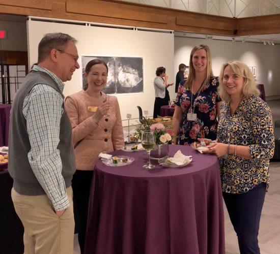 Four people smiling and standing around a cafe table at the 2023 UConn Honors event at the Benton Museum