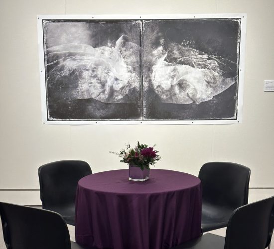 Small banquet table and chairs in front of black and white artwork at the 2023 UConn Honors event in the Benton museum