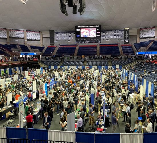 Aerial view of a busy career fair with aisles of company and organization booths set up and crowds of students visiting booths and chatting with representatives