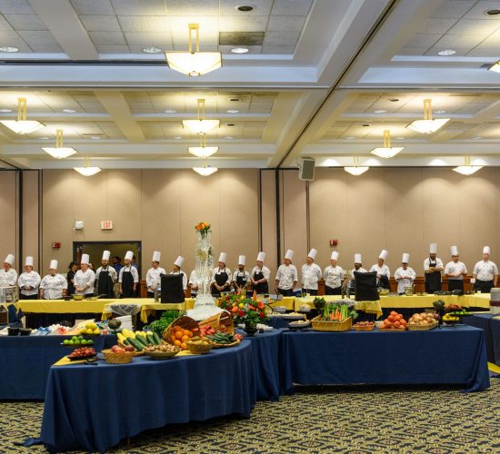 Row of chefs standing behind food displays in Rome ballroom