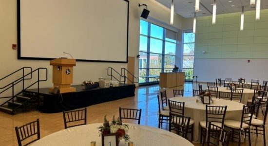 Student Union Ballroom set up with a stage and banquet tables and chairs