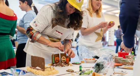 Gingerbread Contest team member in a construction helmet in the early stages of building a gingerbread house at the 2023 Winter Holiday Celebration