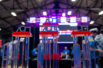 Three 2024 FTC Robotics Tournament trophies. The trophies are clear pedestals with metal geometric shapes atop a red pedestal.