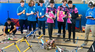 Two teams of robotics students controlling their robots in a competition at the 2024 FTC Robotics Tournament at UConn. One team is wearing blue, the other is wearing pink and black.