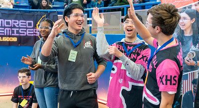 A student robotics team high-fiving and celebrating success after a competition at the 2024 FTC Robotics Tournament at UConn.