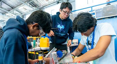 Three members of a robotics team working on their robot at the 2024 FTC Robotics Tournament at UConn.