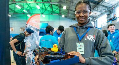 A student holding a box of robotic equipment at the 2024 FTC Robotics Tournament at UConn.